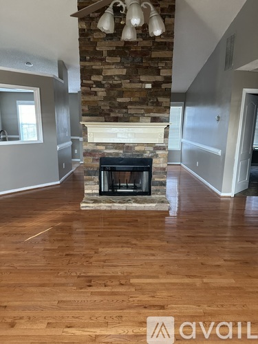 A living room with a stone fireplace and wood flooring.