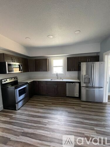 A kitchen with a black stove top oven, a microwave, a sink, and a refrigerator.