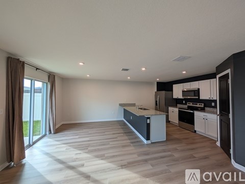 A spacious kitchen and living room with wooden flooring and modern appliances.