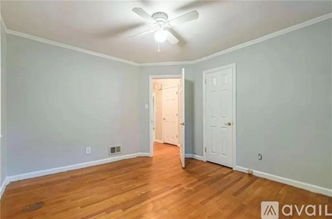 A room with a ceiling fan and wooden flooring.
