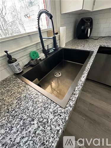 A kitchen sink with a black faucet and a black coffee maker on the counter.