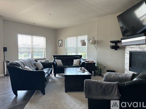 A living room with black furniture and a flat screen TV mounted on the wall.