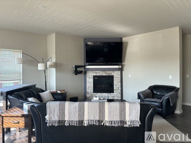 A living room with a fireplace and a television mounted above it.