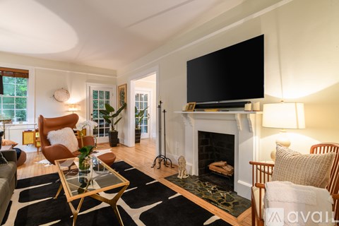 A living room with a fireplace and a large television mounted above it.