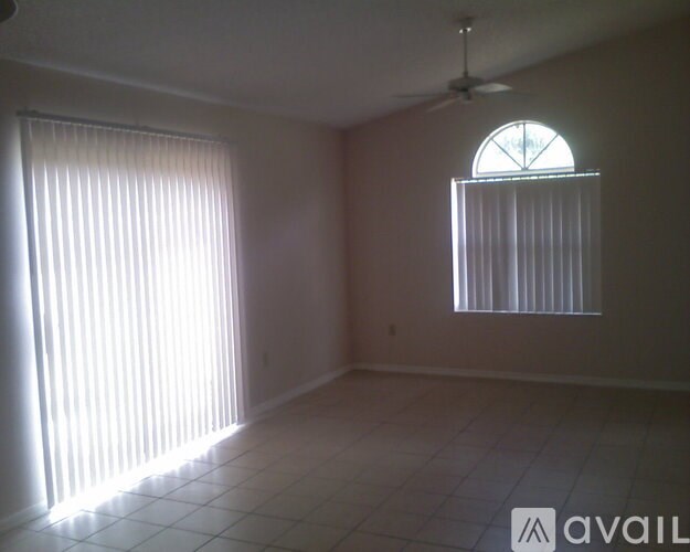 A room with a fan and a window with blinds.