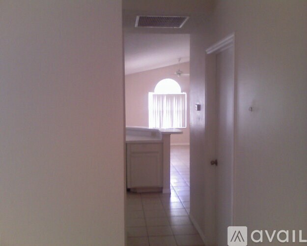 A hallway with a door on the right and a window with blinds on the left.