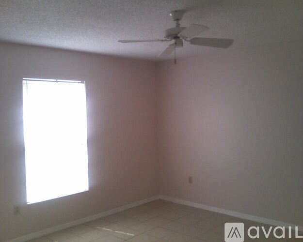 A room with a ceiling fan and a window letting in sunlight.
