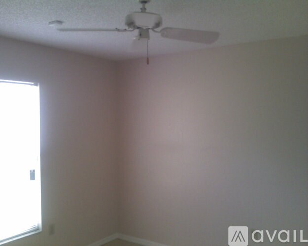 A room with a ceiling fan and a window.