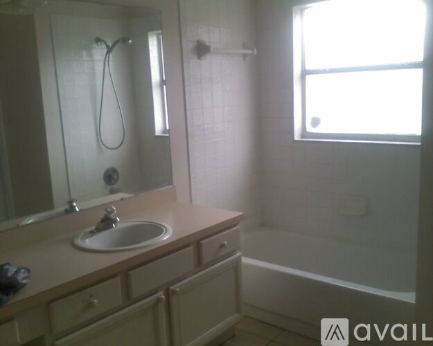 A bathroom with a sink, mirror, and a window.