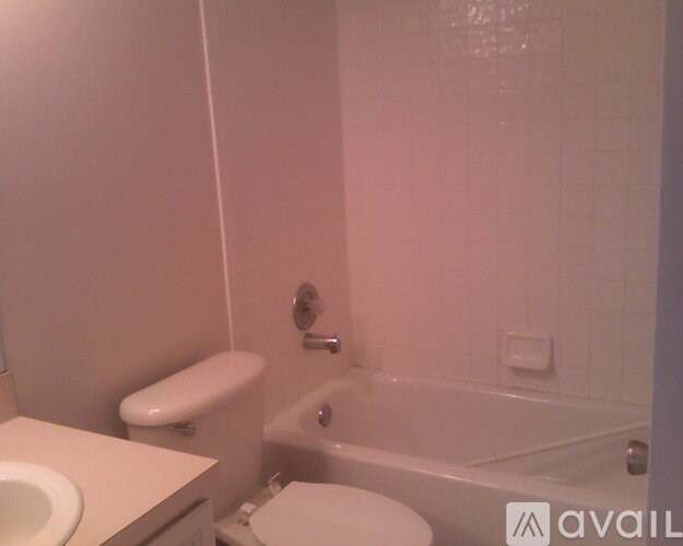 A white toilet sits next to a white bathtub in a bathroom.