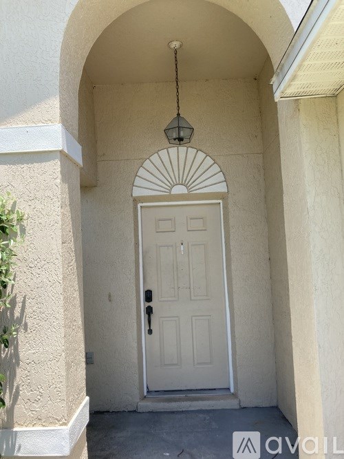A white door is set in a white wall with a hanging light fixture above it.
