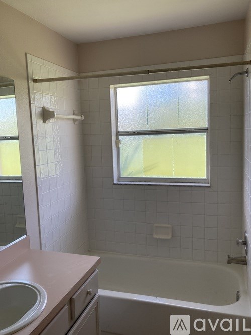 A bathroom with a tub, sink, and window.