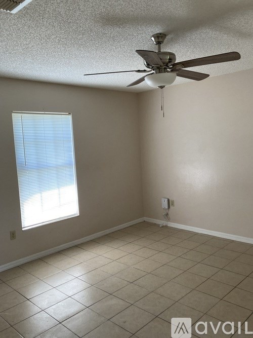 A room with a ceiling fan and a window with blinds.