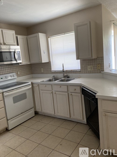 A kitchen with white appliances and cabinets.