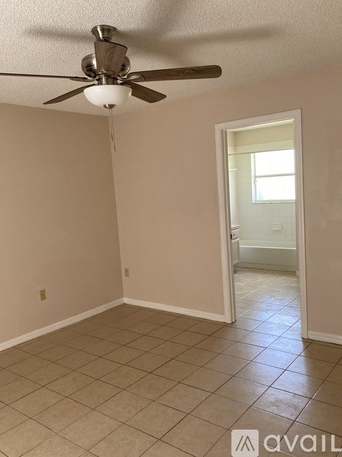A room with a ceiling fan and tile flooring.