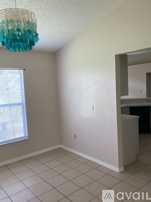 A room with a chandelier and a window with blinds.