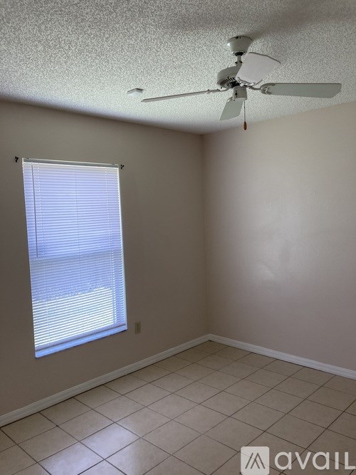 A room with a ceiling fan and a window with blinds.