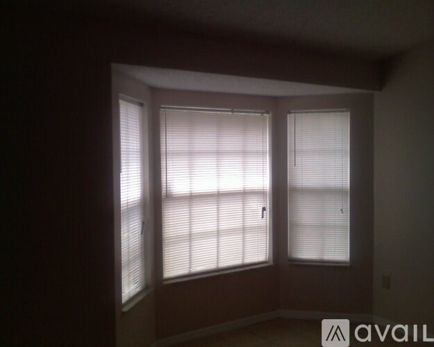 A room with two windows covered in white blinds.