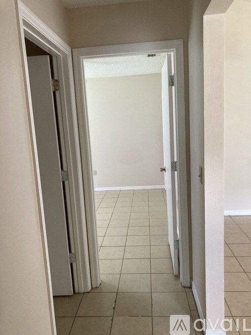 A hallway with a tiled floor and white walls.