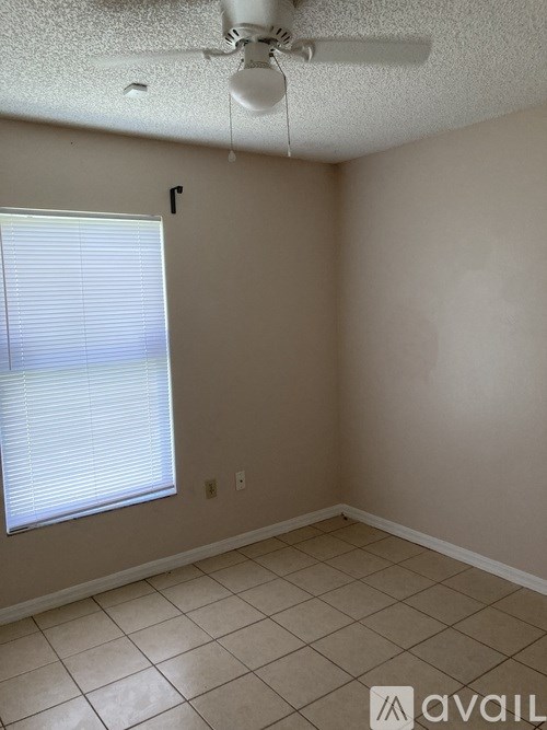 A room with a window covered by blinds and a fan on the ceiling.