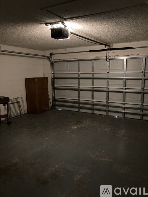 A garage with a closed door and a cabinet on the left.