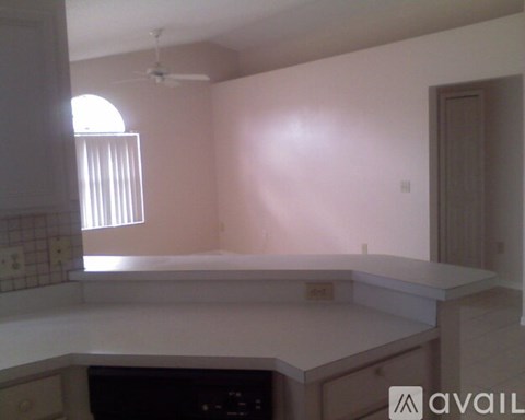 A kitchen with a white countertop and a window with blinds.