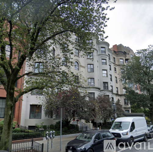 A white van is parked on the street in front of a building.