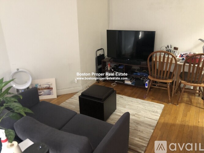 A living room with a grey couch and a black box on the floor.