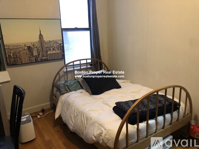 A bedroom with a bed, a chair, and a picture of the Empire State Building on the wall.