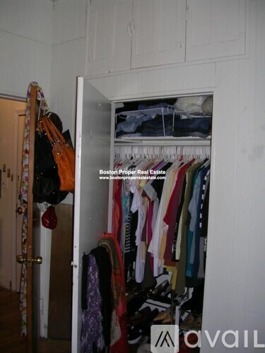 A closet with clothes hanging and a Boston Proper Real Estate sign.