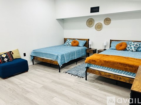 A bedroom with two beds and a bench.