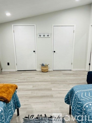 A room with two doors and a bed with a blue blanket.