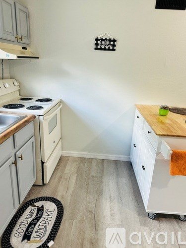 A kitchen with a white stove and white cabinets.