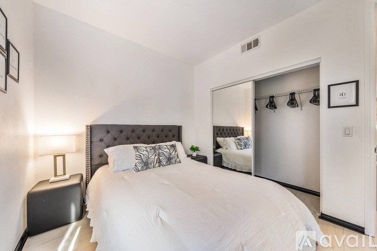 A bedroom with a large bed and a mirrored closet door.