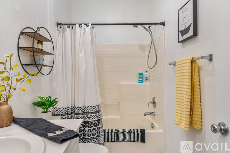 A bathroom with a white tub and a yellow towel hanging on the door.