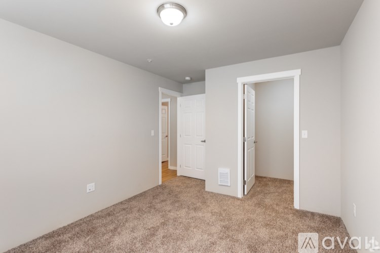 A carpeted room with a doorway leading to another room.