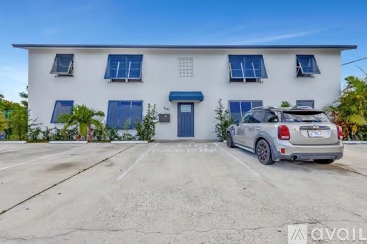 A white house with a blue door and a car parked in front.