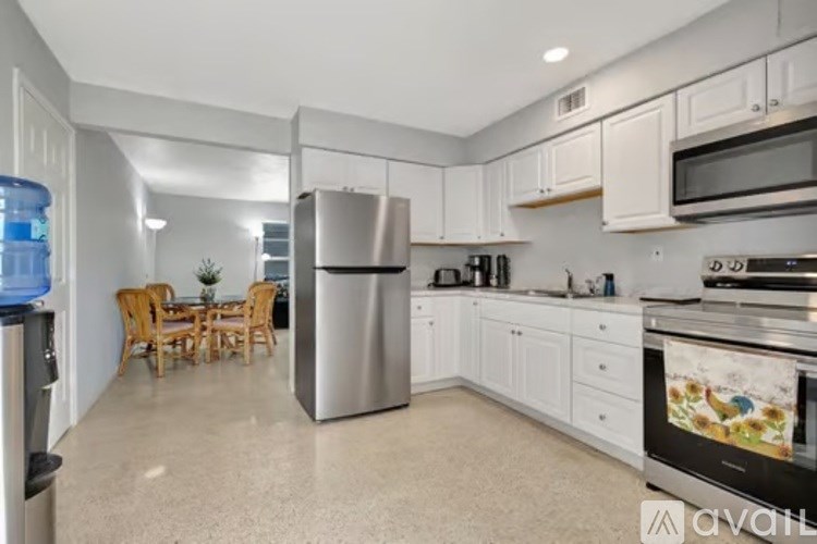 A kitchen with white cabinets and a stainless steel refrigerator.
