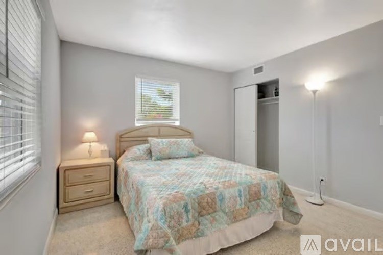 A bedroom with a bed, nightstand, and window.