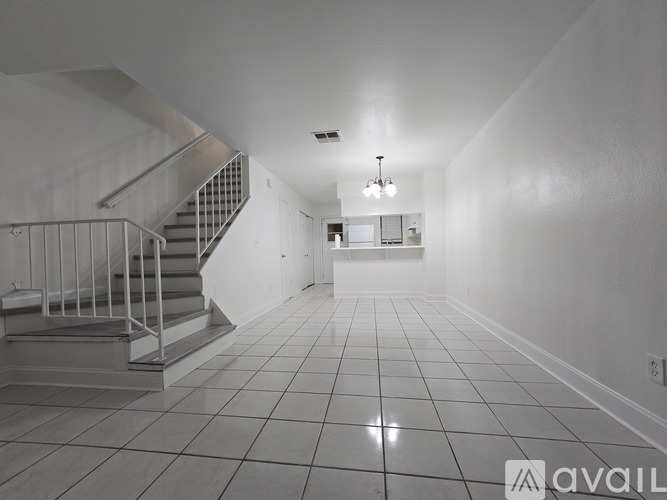 A spacious hallway with a staircase and a chandelier.