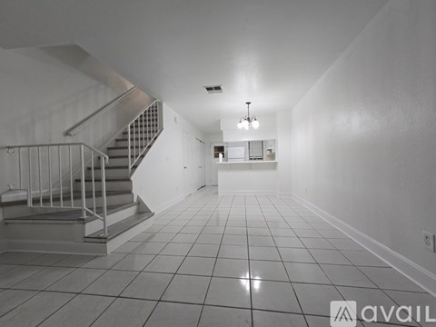 A spacious hallway with a staircase and a chandelier.