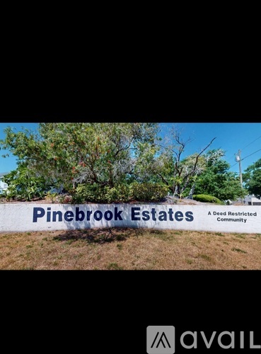 A sign that says Pinebrook Estates in front of some trees.