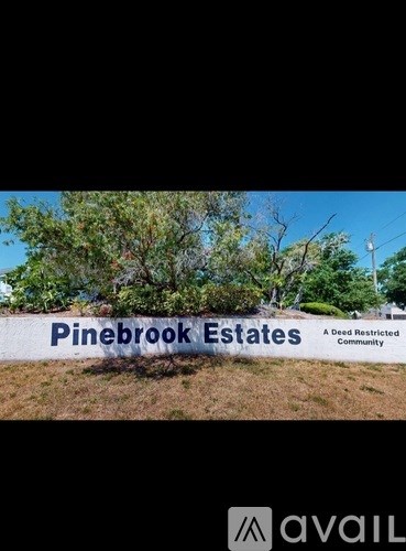 A sign that says Pinebrook Estates in front of some trees.