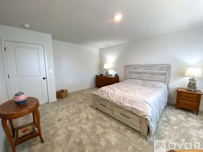 A bedroom with a bed, nightstand, and a table with a bowl on it.