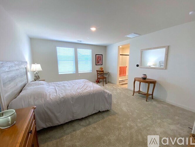 A bedroom with a large bed, a nightstand, a chair, and a small table.