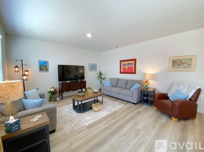 A living room with a grey couch, a brown leather chair, a wooden coffee table, and a television.
