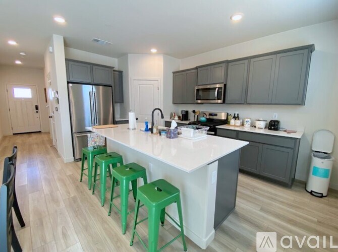 A kitchen with a white countertop and green bar stools.