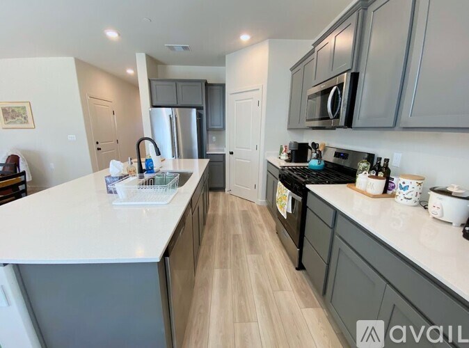 A kitchen with a white countertop and wooden flooring.