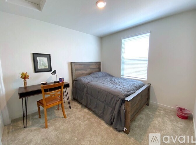 A bedroom with a bed, desk, and chair.