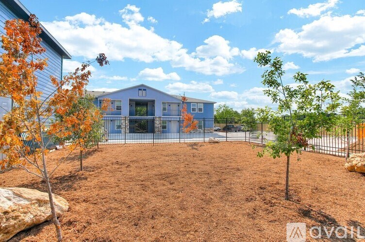 A blue house with a fence and trees in front of it.